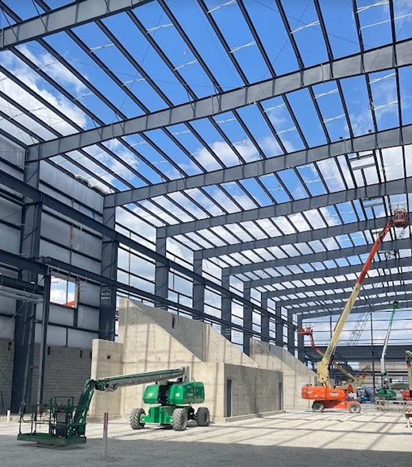 Mascaro Construction structural steel building construction featuring steel framing installation, concrete support structures, and aerial lift equipment during facility development.